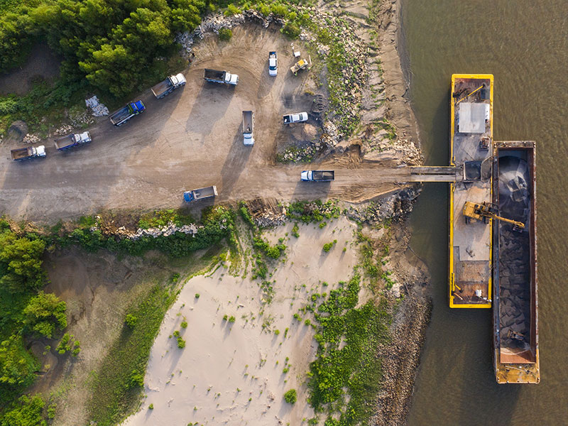 Top-down view of trucks unloading a barge