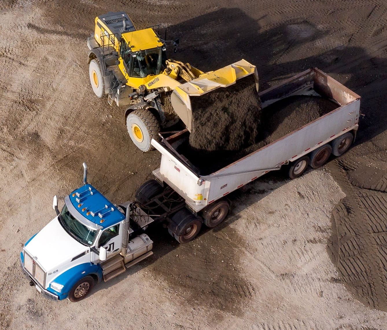 A front loader scooping dirt into a dump truck